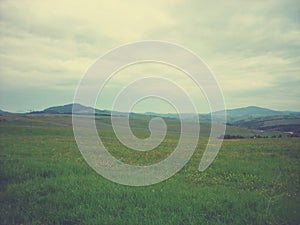 Green spring landscape in the countryside on a cloudy day; panoramic view, retro style