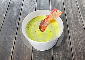 Green spring pea soup with bacon at gray wood