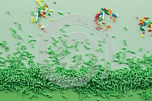 Green sprinkles on two tone green background with multi coloured sprinkles scattered - Top view green sprinkle background with