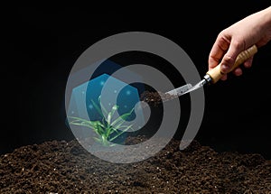 Green sprout in a blue vacuum and a female hand with a shovel of earth on a black background. Environmental protection concept