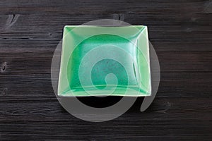 Green square saucer on dark brown table