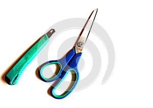 Green stationery knife and blue scissors on a white isolated background. Place for text