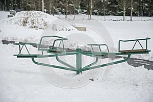 Green steel carousel in the snow without children photo