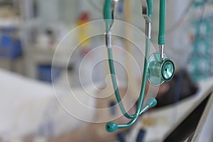 Green stethoscope, on background patient  connected to medical ventilator in ICU in hospital, a place where can be treated