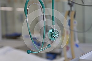 Green stethoscope, on background patient  connected to medical ventilator in ICU in hospital, a place where can be treated photo