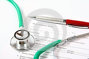 Green stethoscope and a red pen lying on a medical history form