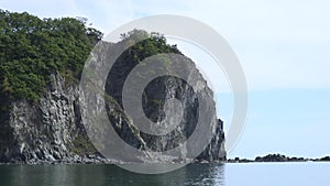 Green stony rocks coastline beach and sea waves water surface in Japan Sea.