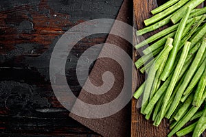 Green string bean, on wooden cutting board, on old dark  wooden table background, top view flat lay, with copy space for text