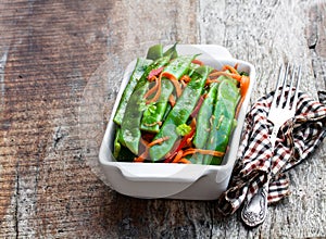 Green string beans and carrot with spices on wooden table