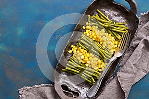 Green string beans and corn. Top view, blue background.