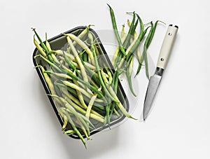 Green string beans in a vintage enameled tray on a light background, top view