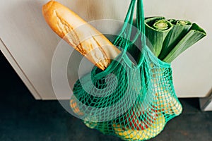 Green string shopping bag hanging on a hook in the kitchen