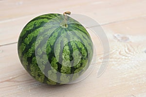 Green striped watermelon on wooden planks background.