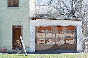 This green stucco building & garage are closed. Door is locked with grass in front.