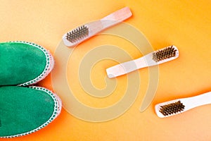 Green suede espadrille shoes with brushes on yellow paper background.