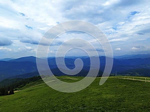 Green summer mountain landscape. Dirt road, footpath at the top of the peak.