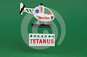 On a green surface, an ambulance helicopter with a sign - Tetanus