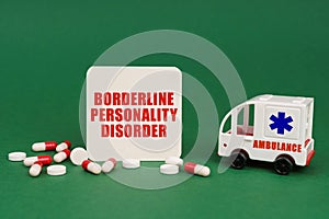 On a green surface, an ambulance, pills and a sign with the inscription - Borderline Personality Disorder