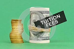 On a green surface are coins and dollars in a bundle. On the dollar sign with the inscription - Tuition Fees