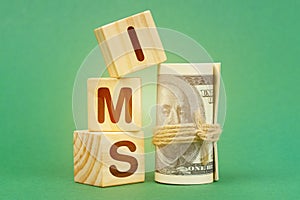 On a green surface, dollars and cubes with the inscription - IMS