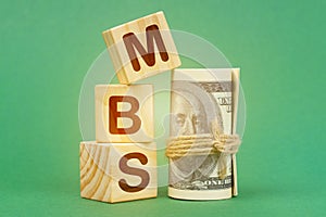 On a green surface, dollars and cubes with the inscription - MBS