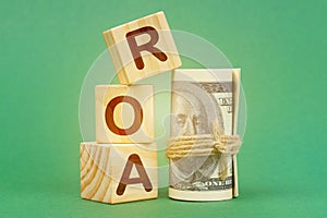 On a green surface, dollars and cubes with the inscription - ROA