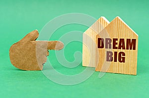 On a green surface, a hand points to a house with an inscription - Dream Big