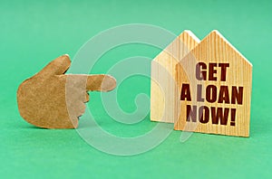 On a green surface, a hand points to a house with an inscription - Get a Loan Now