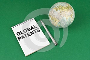 On a green surface lies a model of the planet and a notepad with the inscription - Global Patents