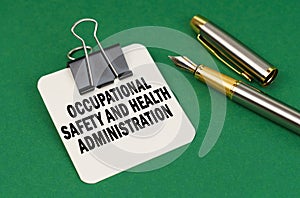 On a green surface, a pen and a sheet of paper with the inscription - Occupational Safety and Health Administration