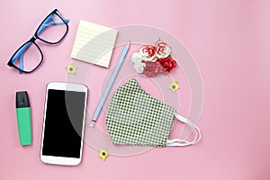 Green surgical mask plaid and blue glasses with pencil mobile clipping path screenflower on pink backgroud pastel style flatlay