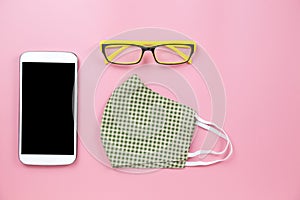 Green surgical mask plaid and yellow glasses with mobile clipping path screenon pink backgroud pastel style flatlay topview