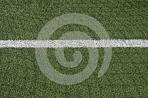 Green synthetic artificial grass football or soccer field with white line and shadow from football goal net in sunny day