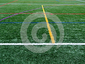 Green synthetic grass sports field with colorful lines
