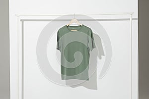 Green t shirt on hanger hanging from clothes rail with copy space on white background