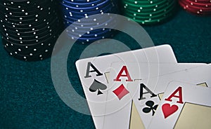 on the green table, highlights a set of four aces, in poker game next to the colored chips