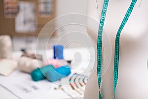 Green tape measure and mannequin with pins in professional sewing atelier dressmaker equipment