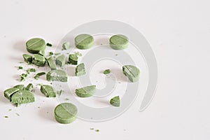 Green targets and crushed pills on a white background. . Concept of medicine. Close-up