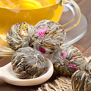 Green tea balls with flowers, tea cup and wooden spoon