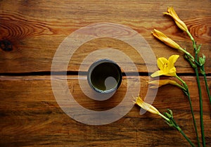 Green tea bowl on a dark brown wooden background with beautiful yellow lilies