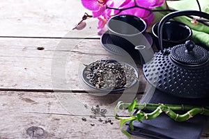 Green tea in bowl and traditional asian tea set on aged wooden