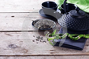 Green tea in bowl and traditional asian tea set on aged wooden