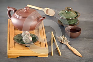 Green tea buds, ceramic teapot, cups, wooden tea tray and other attributes for a traditional tea ceremon