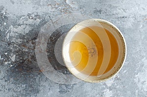 Green tea in clay cup on gray painted wooden backdrop. Top view