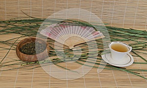 Green tea in a Cup, outdoor fan on bamboo Mat