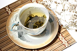 Green tea in a cup with a tea leafs