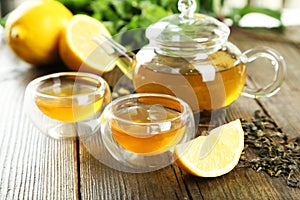 Green tea in cup and teapot on brown wooden background