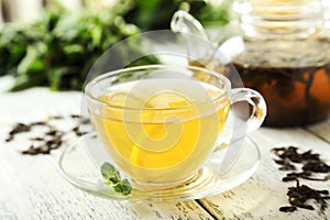 Green tea in cup and teapot on white wooden background