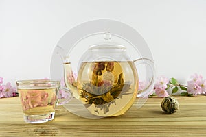 Green tea with flower bloom inside a glass teapot