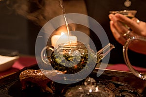 Green tea, glass teapot with tea leaves, tea is poured into a cup at a tea ceremony
